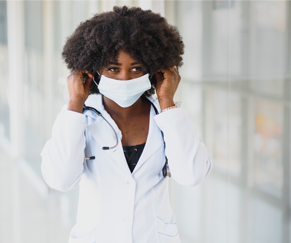 Black provider putting on a mask in clinic hallway