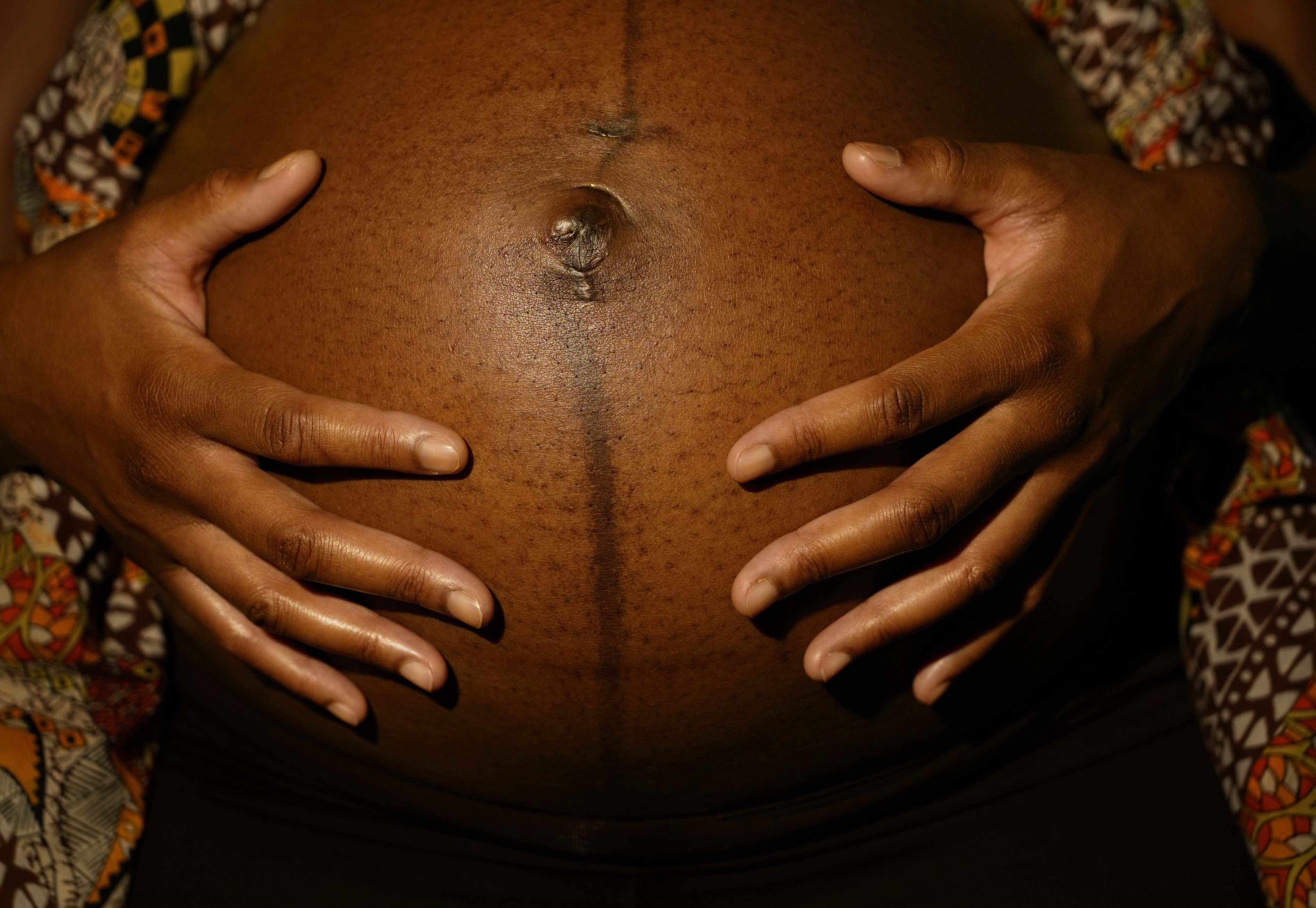 Black woman's hands on her pregnant belly