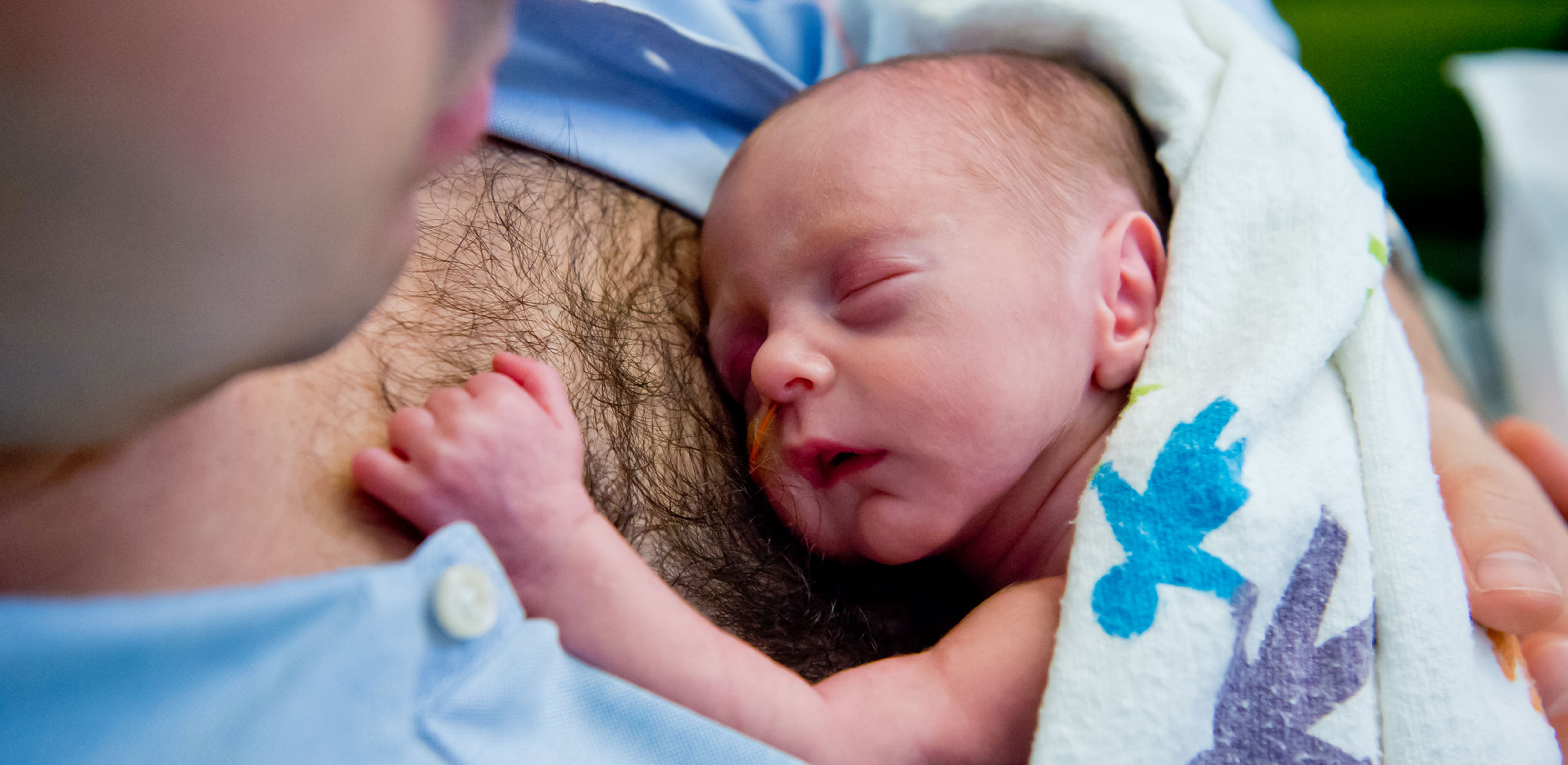 A preemie lies on it's father's bare chest